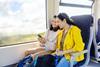Two woman friends travelling by train looking at cell phone