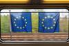 Two European flags hanging in a train window