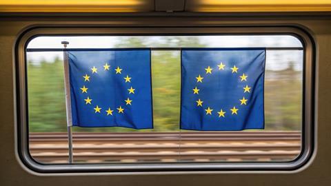 Two European flags hanging in a train window